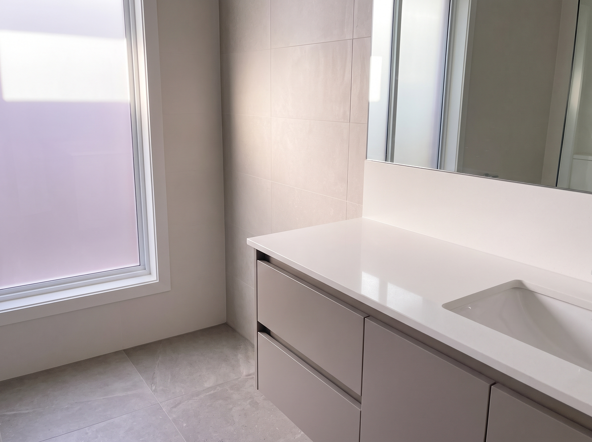 A clean bathroom vanity with bare wall space beside the mirror